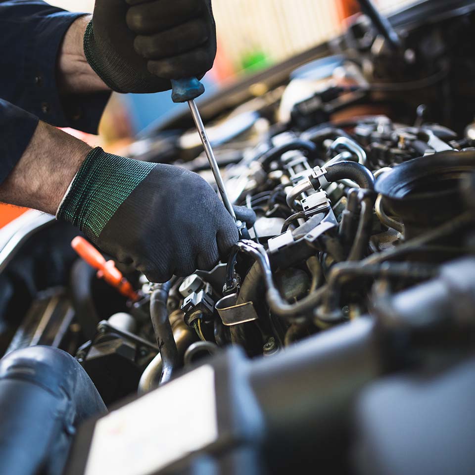 Close up hands of unrecognizable mechanic doing car service and maintenance.