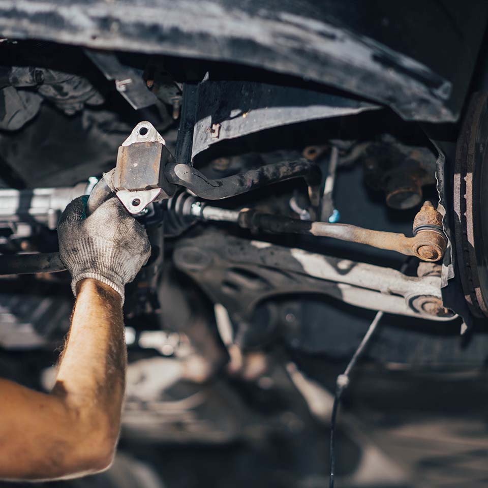 car suspension diagnostics, auto mechanic touches suspension arms and silent blocks