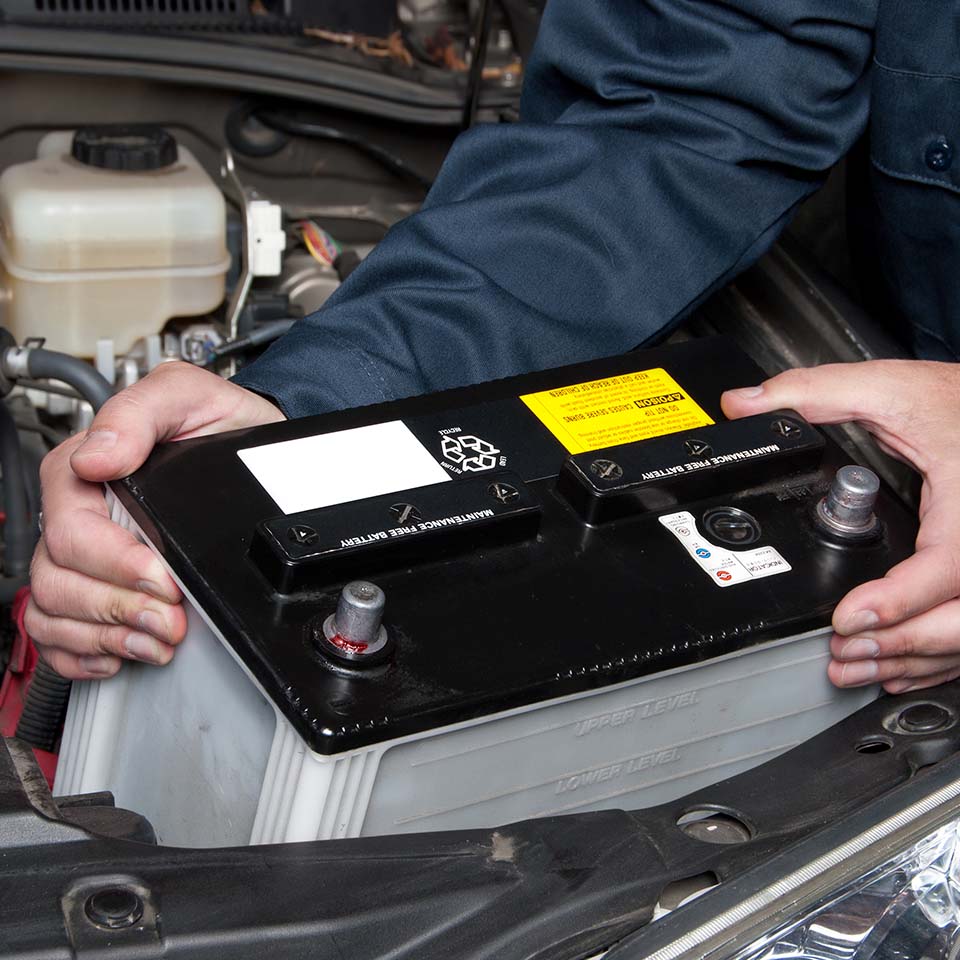 A car mechanic replaces a battery during maintenance.